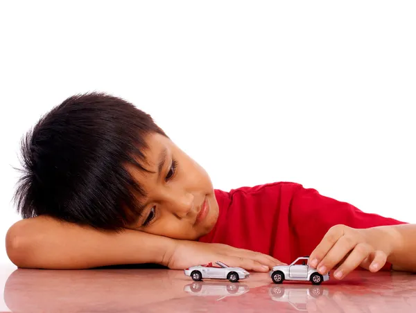 Młody chłopak, spychając swoje samochody na stole — Zdjęcie stockowe