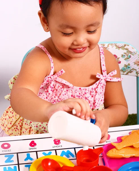 Małe dziecko grając na wylewanie filiżankę herbaty — Zdjęcie stockowe