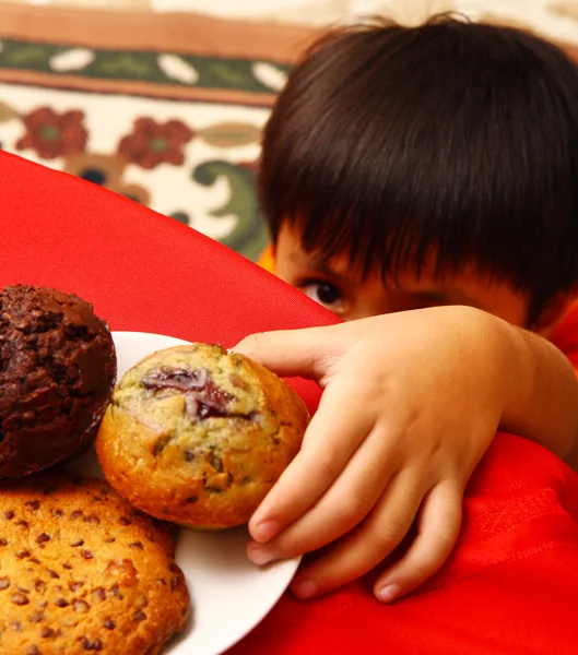 Непослушный ребенок берет торт со стола — стоковое фото
