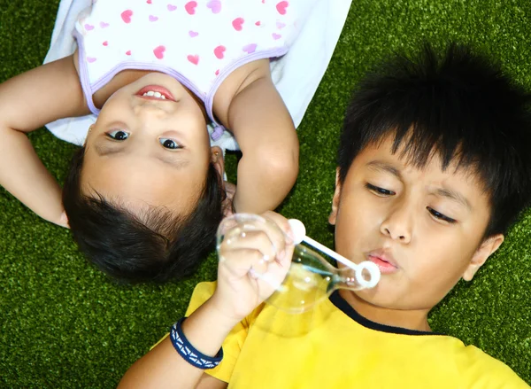 Двое детей лгут и играют на траве — стоковое фото