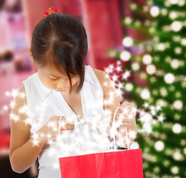 Aufgeregtes Mädchen betrachtet ihr funkelndes Weihnachtsgeschenk — Stockfoto