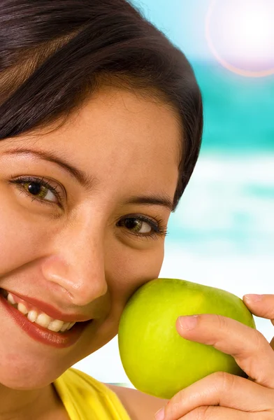Молода усміхнена леді на пляжі тримає яблуко — стокове фото