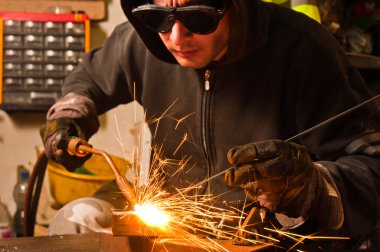 Worker welding with hot flame and sparks clipart