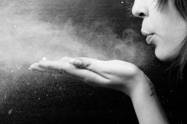 Woman blowing white powder on black background — Stock Photo, Image