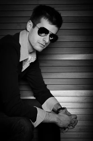 Young man sitting in the window with sunglasses in black and whi — Stock Photo, Image