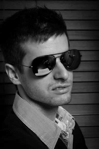 Primer plano de un joven en gafas de sol contra persianas en negro y —  Fotos de Stock