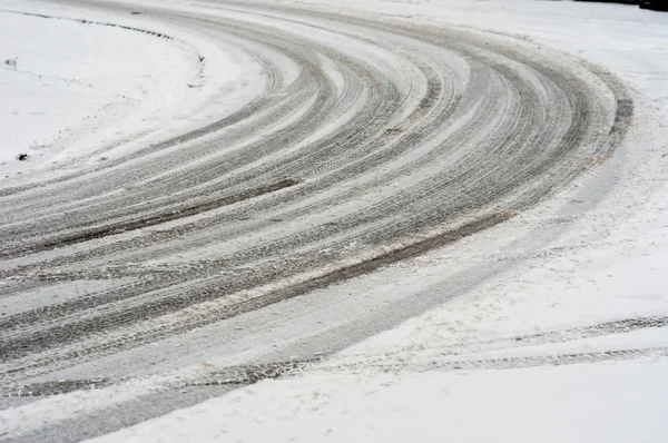 Curva in strada coperta di neve con pista — Foto Stock