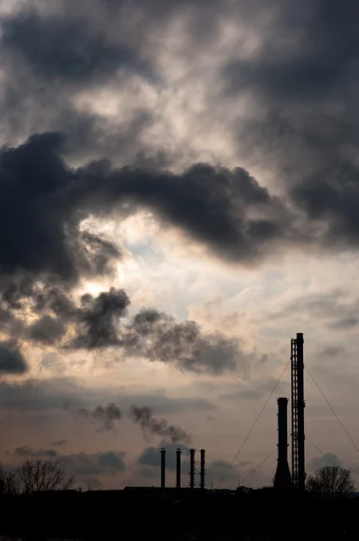 Silouette of a powerplant with smoke coming out of chinney — Stock Photo, Image