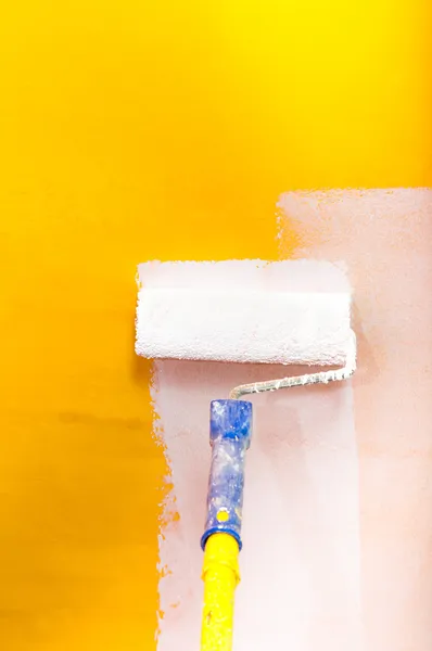 White paint over yellow wall with painting rod — Stock Photo, Image