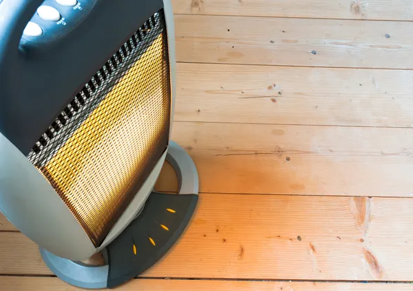 Um halogéneo ou aquecedor eléctrico no chão de madeira — Fotografia de Stock