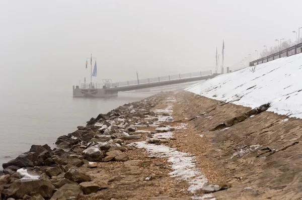 Грязный берег в тумане с причалом на заднем плане — стоковое фото