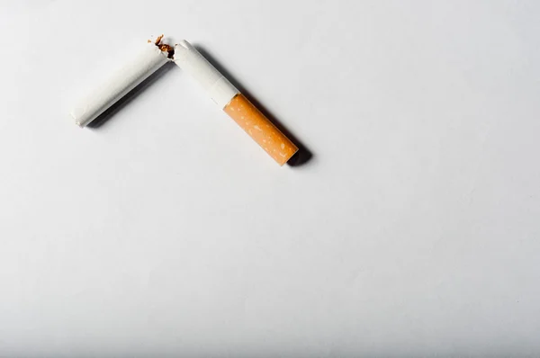 Разбитая сигарета на белом фоне с резкими тенями — стоковое фото
