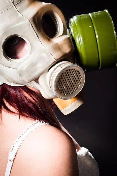 Girl wearing gasmask and white lingerie holding her head — Stock Photo, Image