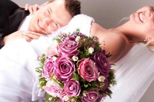 Young couple in wedding wear with bouquet of roses — Stock Photo, Image