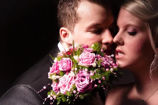 Jeune couple en tenue de mariage avec bouquet de roses — Photo