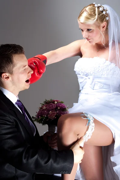 Молодая невеста бьет жениха, пока он снимает свадебную подвязку — стоковое фото