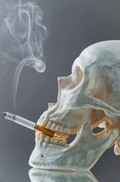 Skull with burning cigarette in mouth — Stock Photo, Image