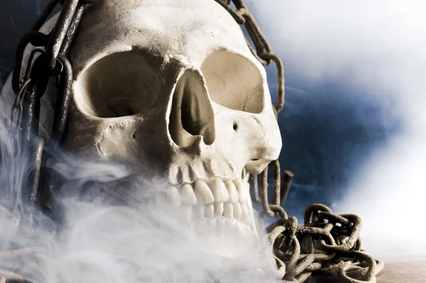 Череп человека с цепью и дымом — стоковое фото