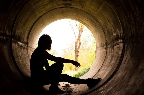 Silhouette eines jungen Mädchens, das in Abwasserrohr raucht — Stockfoto