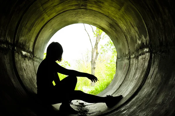 Silhouette of a young girl smoking in sewer pipe — Stock Photo, Image