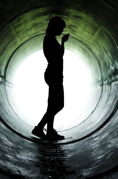 下水道管路内での喫煙少女のシルエット — ストック写真