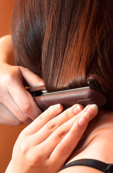 Ragazza che utilizza il ferro sui capelli — Foto Stock