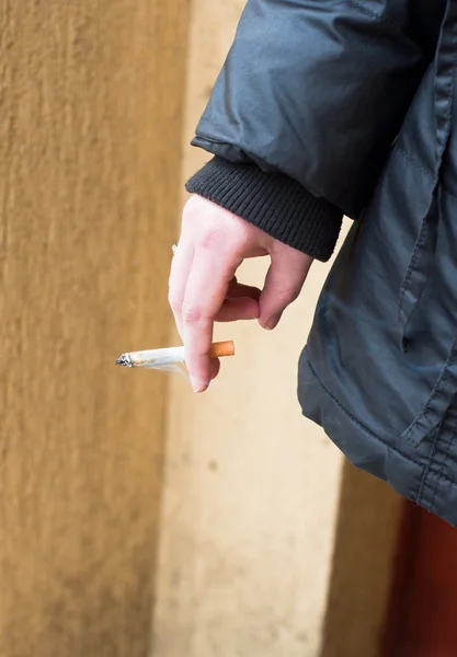 Girl holding cigarette in jacket — Stockfoto