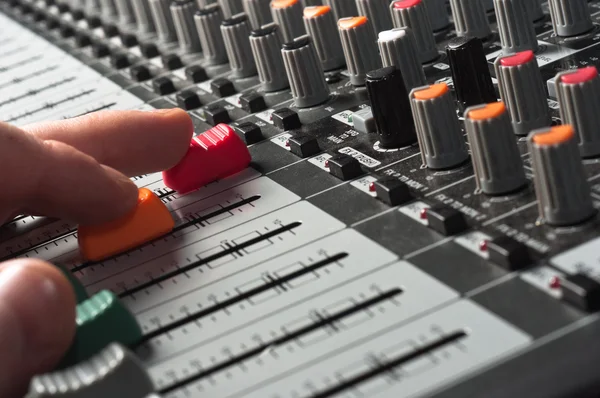 Part of an audio sound mixer with buttons and sliders and hand — Stock Photo, Image