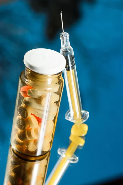 Medicine bottle with sirynge on blue background with reflection — Stock Photo, Image