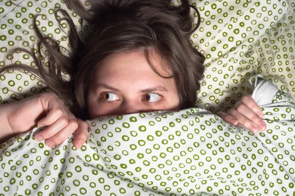 Mädchen versteckt sich zu Hause im Bett unter der Decke — Stockfoto