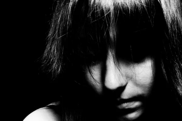 Ein trauriges Mädchen, das mit unsichtbaren Augen in schwarz-weiß nach unten schaut — Stockfoto