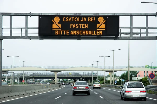 Varovným signálem na dálnici s některých aut na silnici — Stock fotografie