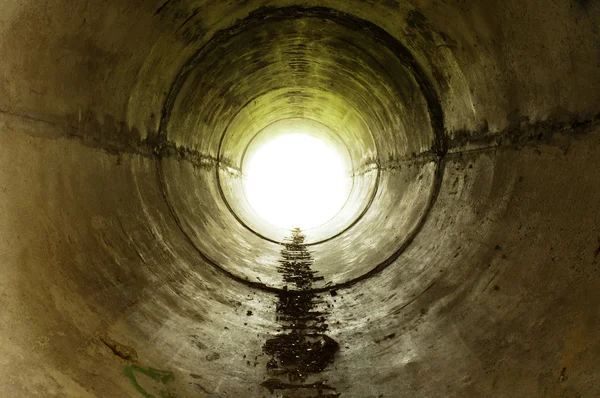 Um túnel industrial que conduz à luz — Fotografia de Stock