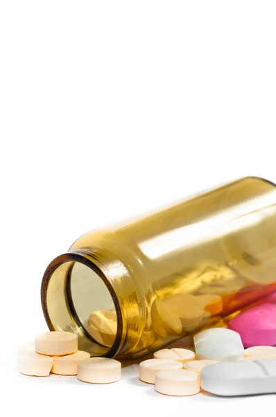 Frasco de medicamento com comprimidos roxos e amarelos contra isola branca Fotografia De Stock