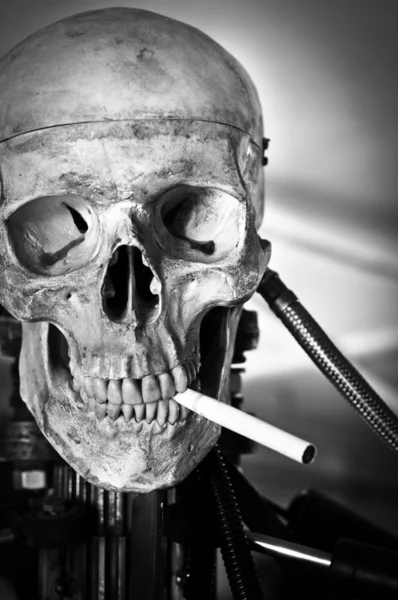 Ağzında sigara olan robot gövde üzerinde bir insan kafatası closeup — Stok fotoğraf