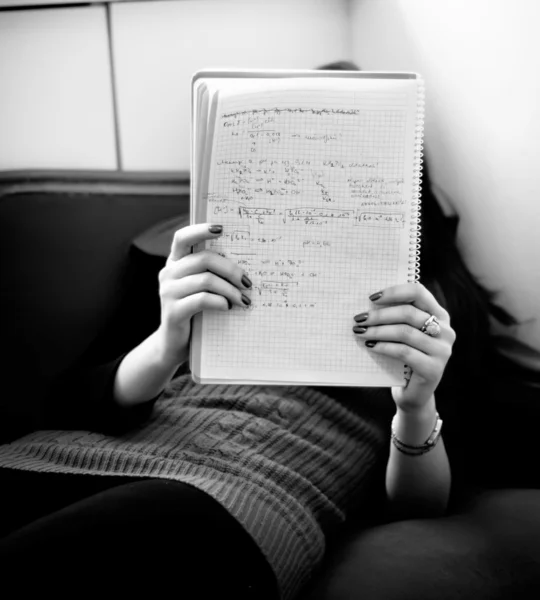 Chica joven leyendo notas en un sofá —  Fotos de Stock