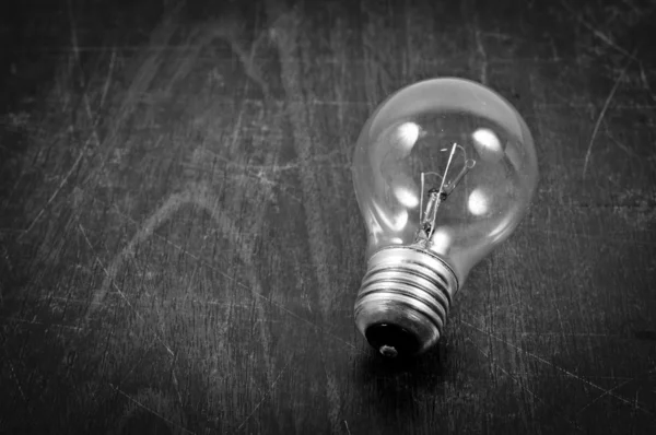 Light bulb on wooden plate in black and white — Stock Photo, Image