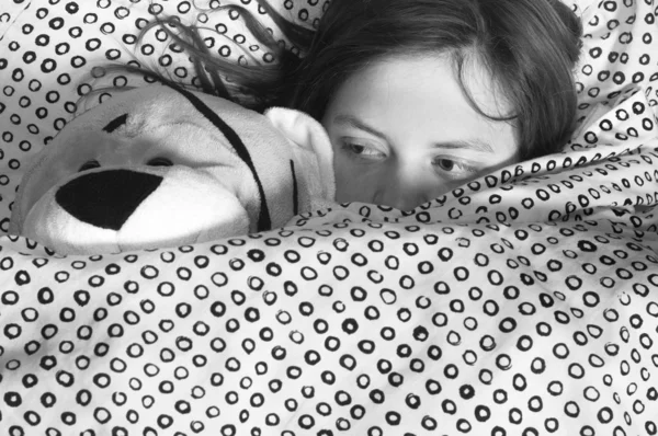 Jovem na cama segurando ursinho de pelúcia — Fotografia de Stock