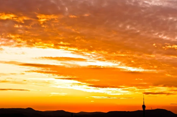 Silhoutette de algunas montañas una torre da con cielo anaranjado — Foto de Stock