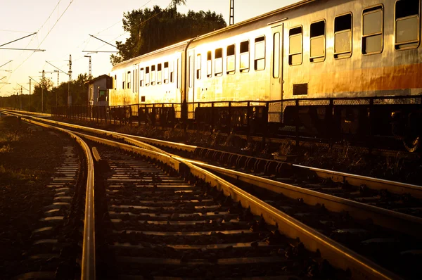 Trein passerende in oranje zonsondergang — Stockfoto