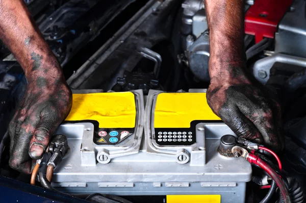 Инженер с маслом на руках держит аккумулятор автомобиля крепко — стоковое фото