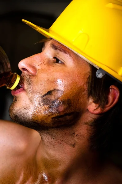 Промышленный рабочий с маслом на лице, пьющий после работы — стоковое фото