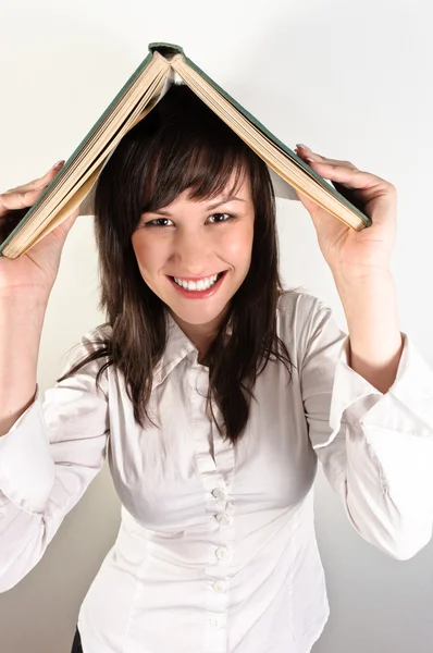 Estudante menina segurando livro em sua cabeça — Fotografia de Stock