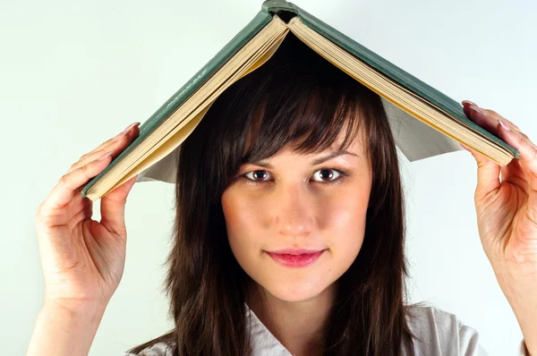 Beautiful young girl hiding under book — Stock Photo, Image