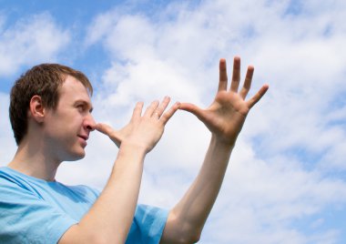 The young man plays about and wriggles against the blue sky clipart