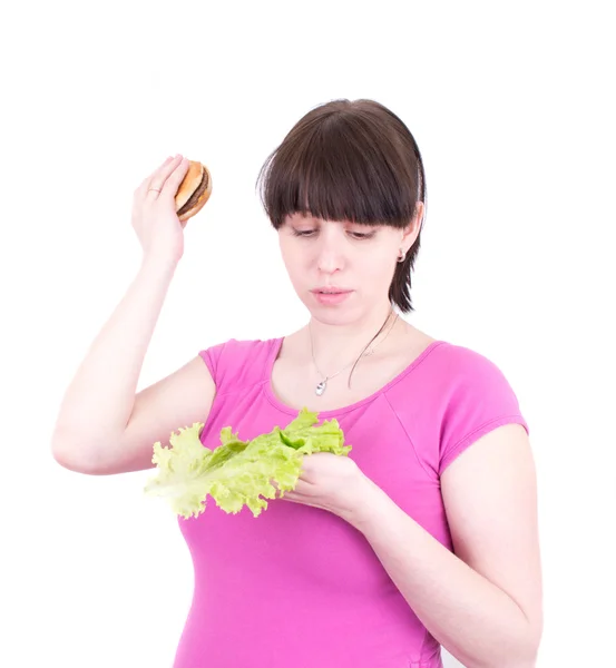 stock image The young woman throws out a hamburger holding salad