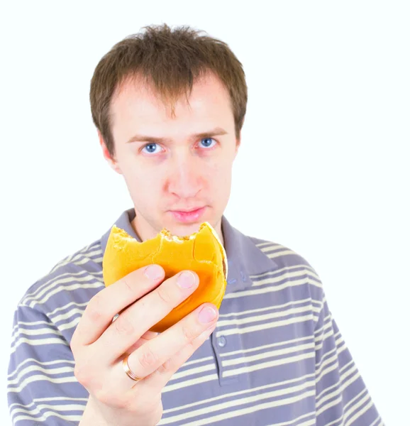 stock image The young man eats a hamburger. Focus on hamburger.