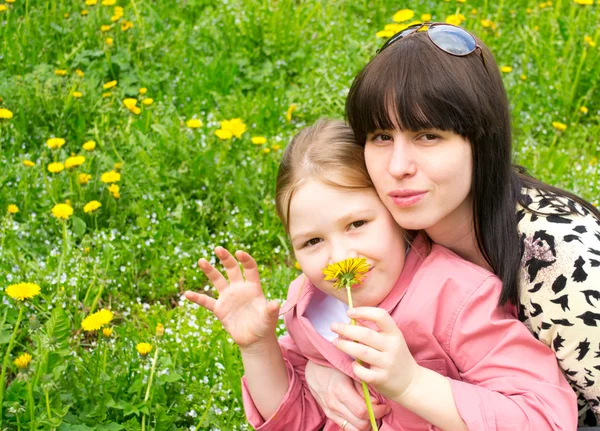 Mother and the daughter on a green meadow with dandelions