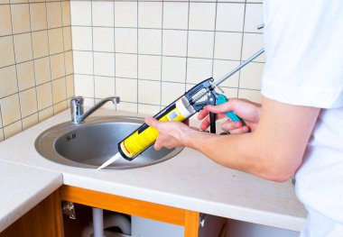 Caulking gun putting silicone sealant to installing a kitchen si clipart