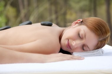 Beautiful woman having a hot stones massage clipart